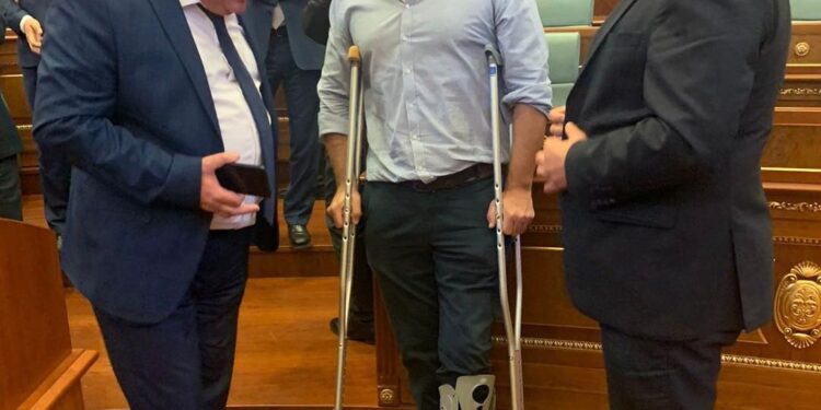 Deputeti i PDK’së shfaqet me paterica e këmbë të lënduar në seancën e Kuvendit